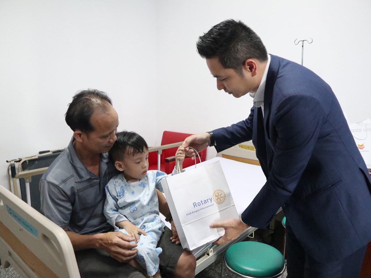 Hoa Nguyen remet un cadeau à un père et son enfant en convalescence dans un hôpital cardiologique de Hô Chi Minh-Ville