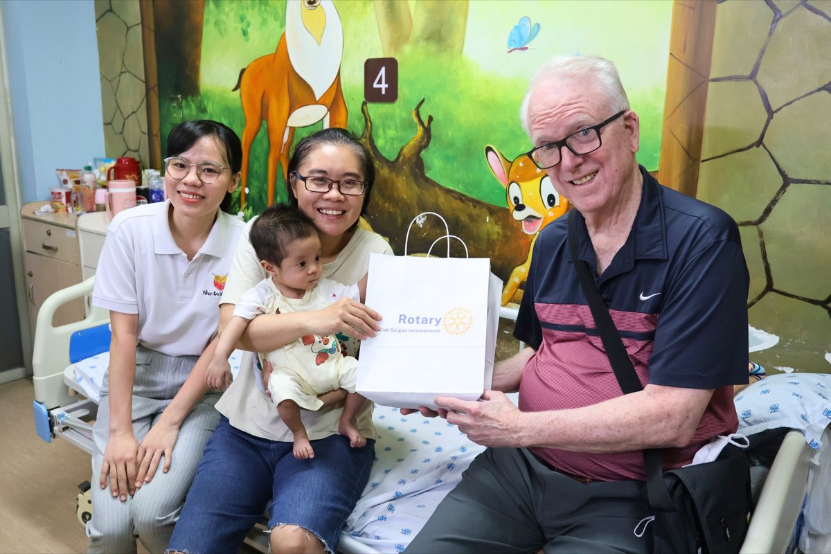 Le Dr Robert Ashley remet un cadeau à la mère d’un enfant en convalescence, accompagné d’une bénévole de la fondation VinaCapital